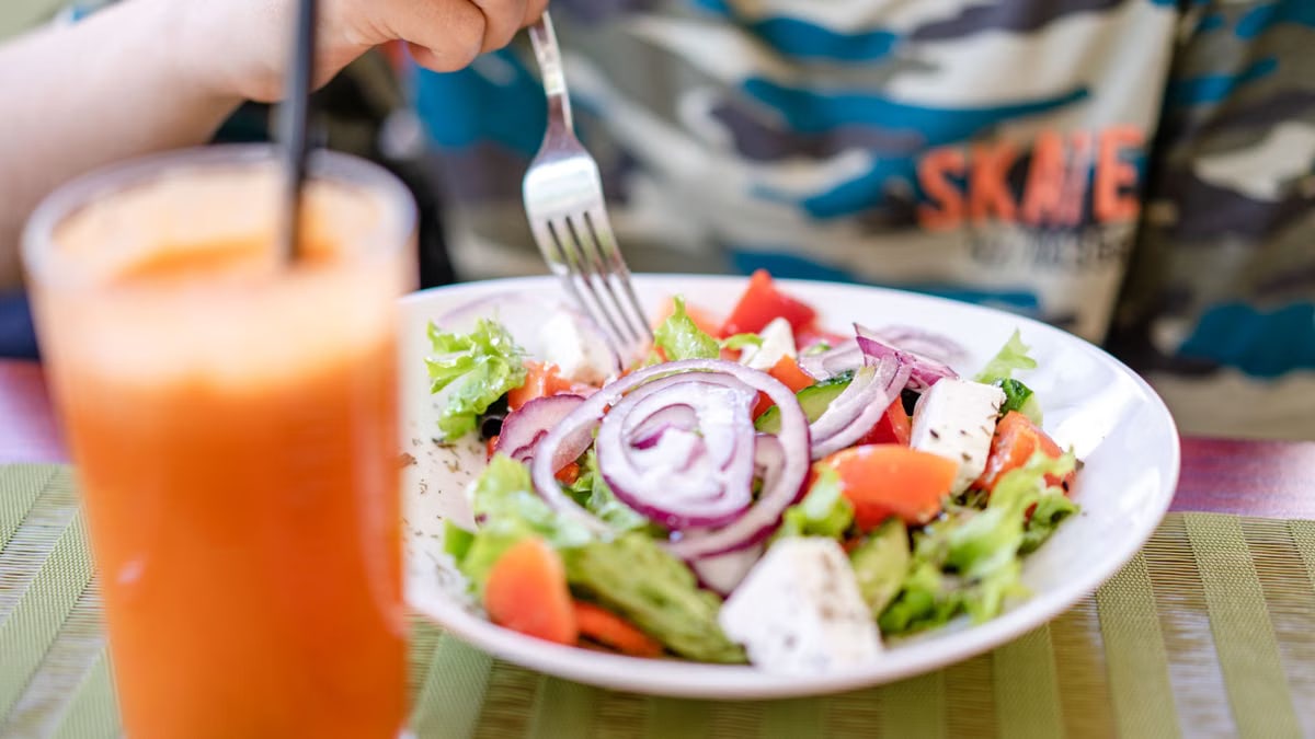 Colorful salad with fresh vegetables and a refreshing drink on a table.