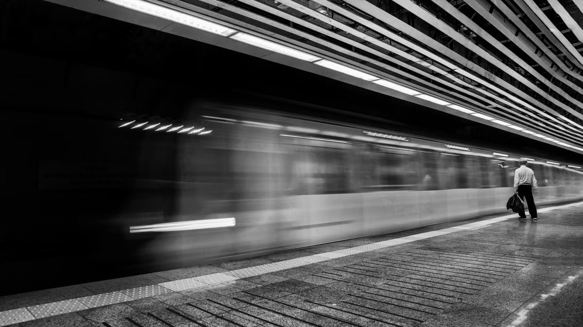 Motion blur of a speeding subway train with a solitary passenger on the platform.